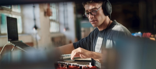 A person wearing headphones and sitting at a desk with a computer  Description automatically generated with medium confidence